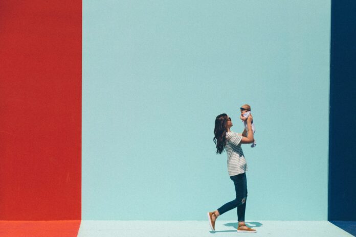 A joyful mother raises her smiling baby high in the air, celebrating the bond between mother and child, while highlighting the importance of postpartum nutrition.