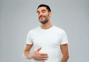 A man smiling with relief, holding his stomach,