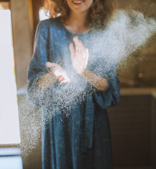 Close-up of woman's hands dusting with visible Tyndall effect, showing allergen particles in the air