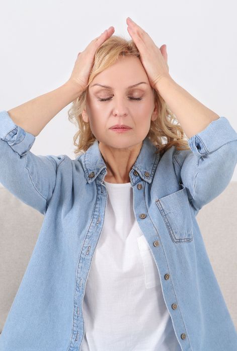 A person experiencing an anxiety attack, holding their head with their palms on their temples, as if trying to relieve pressure or pain.