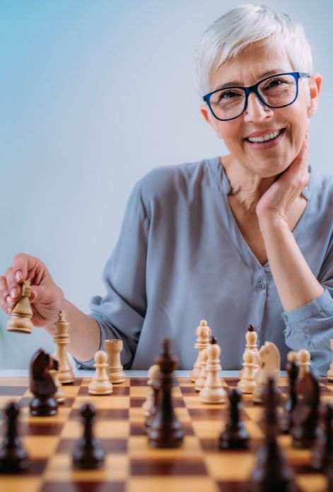 an older woman playing chess to improve neurocognitive conditions