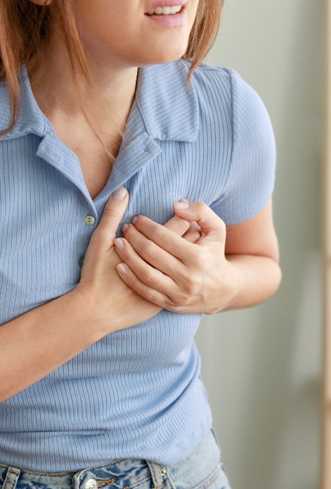 A person clutching their chest, experiencing shortness of breath, and holding a blood pressure monitor, depicting common cardiometabolic disease symptoms.