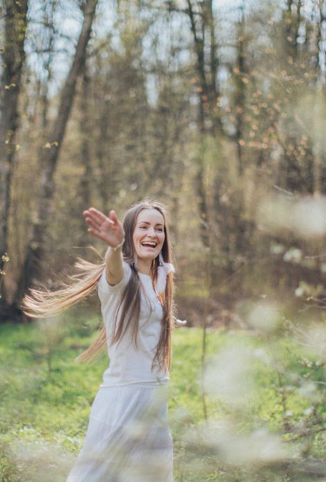 A woman dances joyfully in a field of flowers, surrounded by pollen, her face expressing pure happiness and freedom from allergy symptoms.